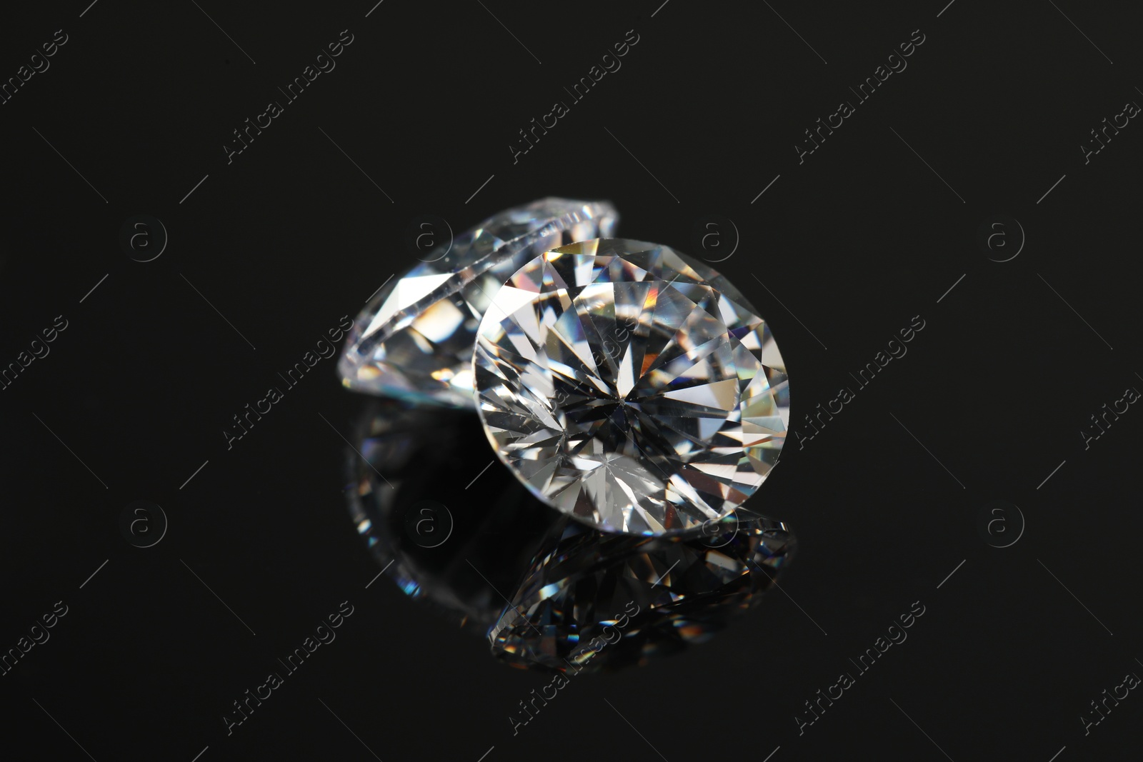 Photo of Beautiful shiny diamonds on black mirror surface, closeup