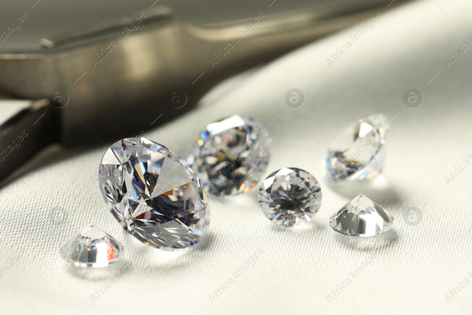 Photo of Many beautiful shiny diamonds on white fabric, closeup