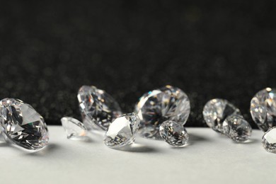 Photo of Beautiful dazzling diamonds on light grey table, closeup