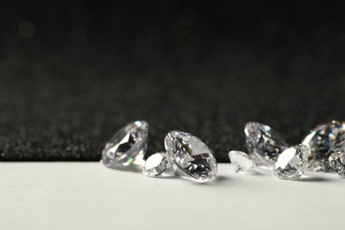 Photo of Beautiful dazzling diamonds on light grey table, closeup