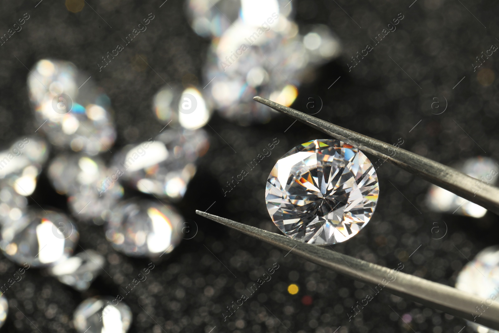 Photo of Tweezers with beautiful diamond on blurred background, closeup