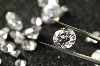 Tweezers with beautiful diamond on blurred background, closeup