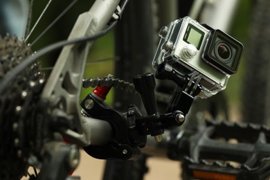 Photo of Modern action camera with mount on bicycle outdoors, closeup