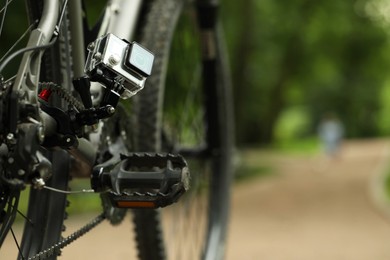 Modern action camera with mount on bicycle outdoors. Space for text