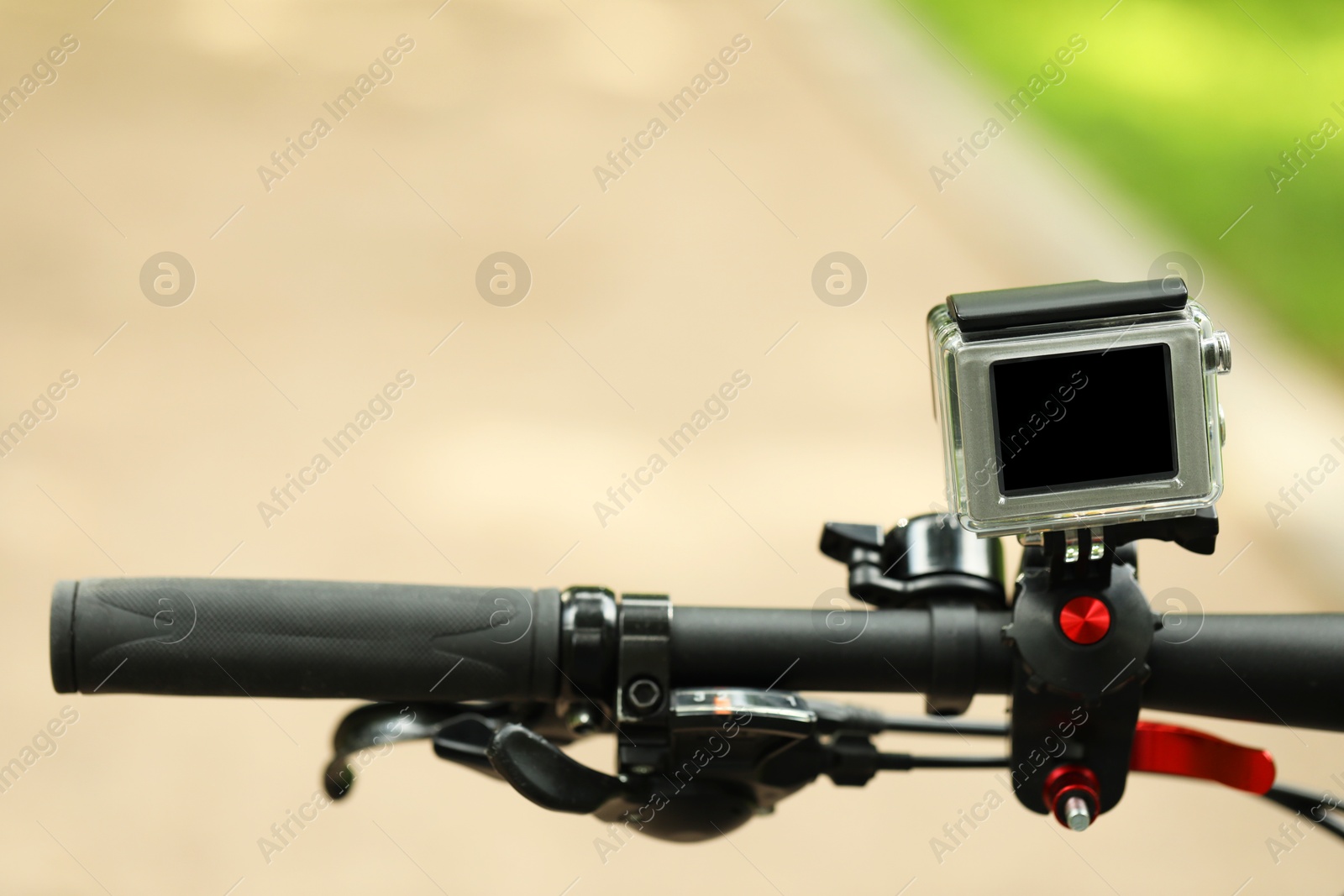 Photo of Modern action camera with mount on bicycle outdoors, closeup