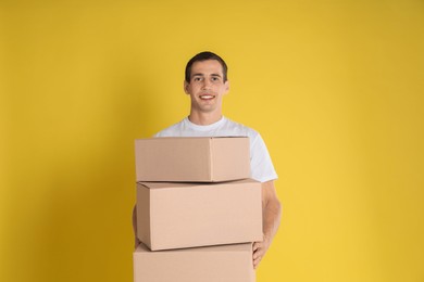 Photo of Moving into new house. Man with cardboard boxes on yellow background