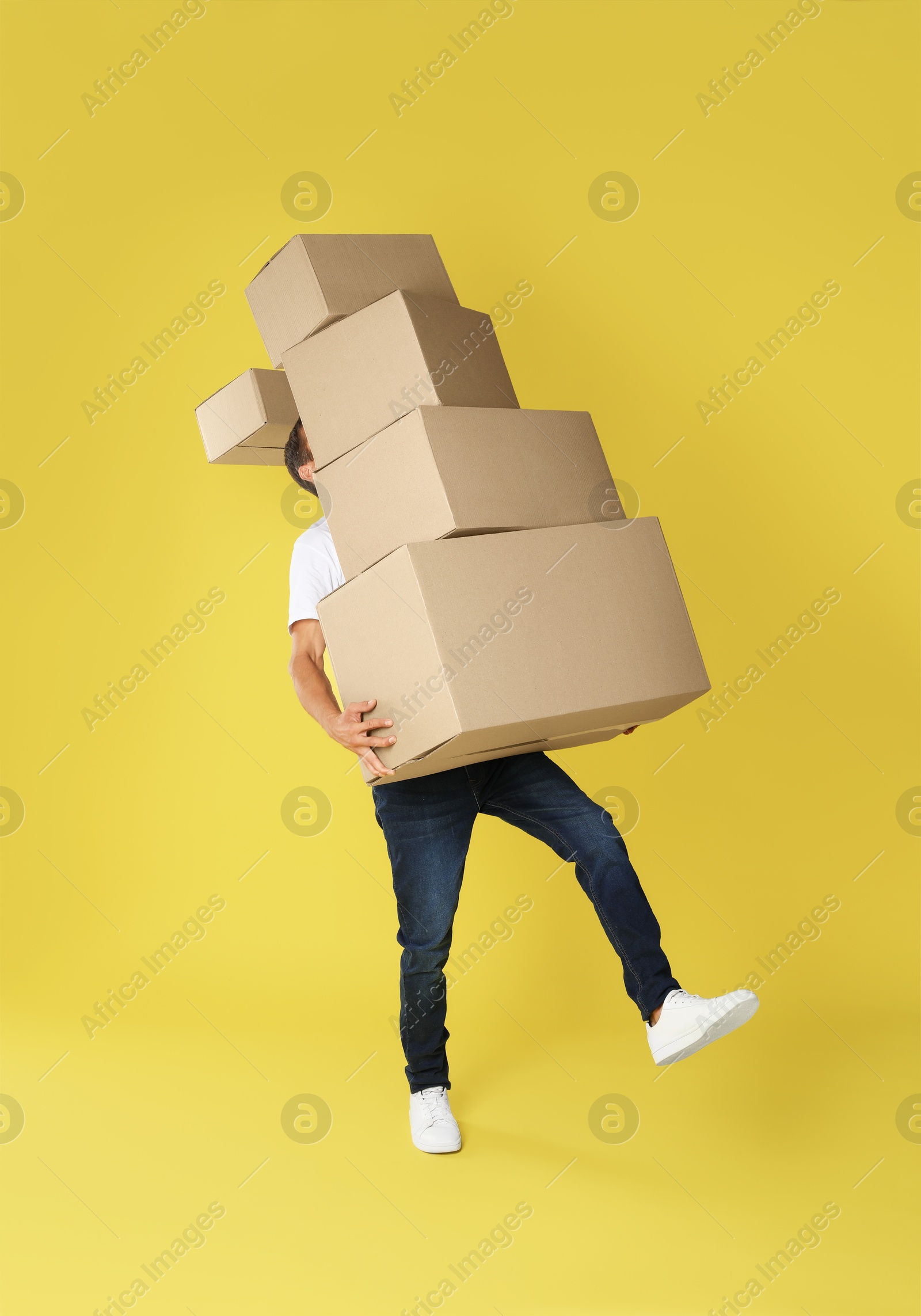 Photo of Moving into new house. Man with cardboard boxes on yellow background