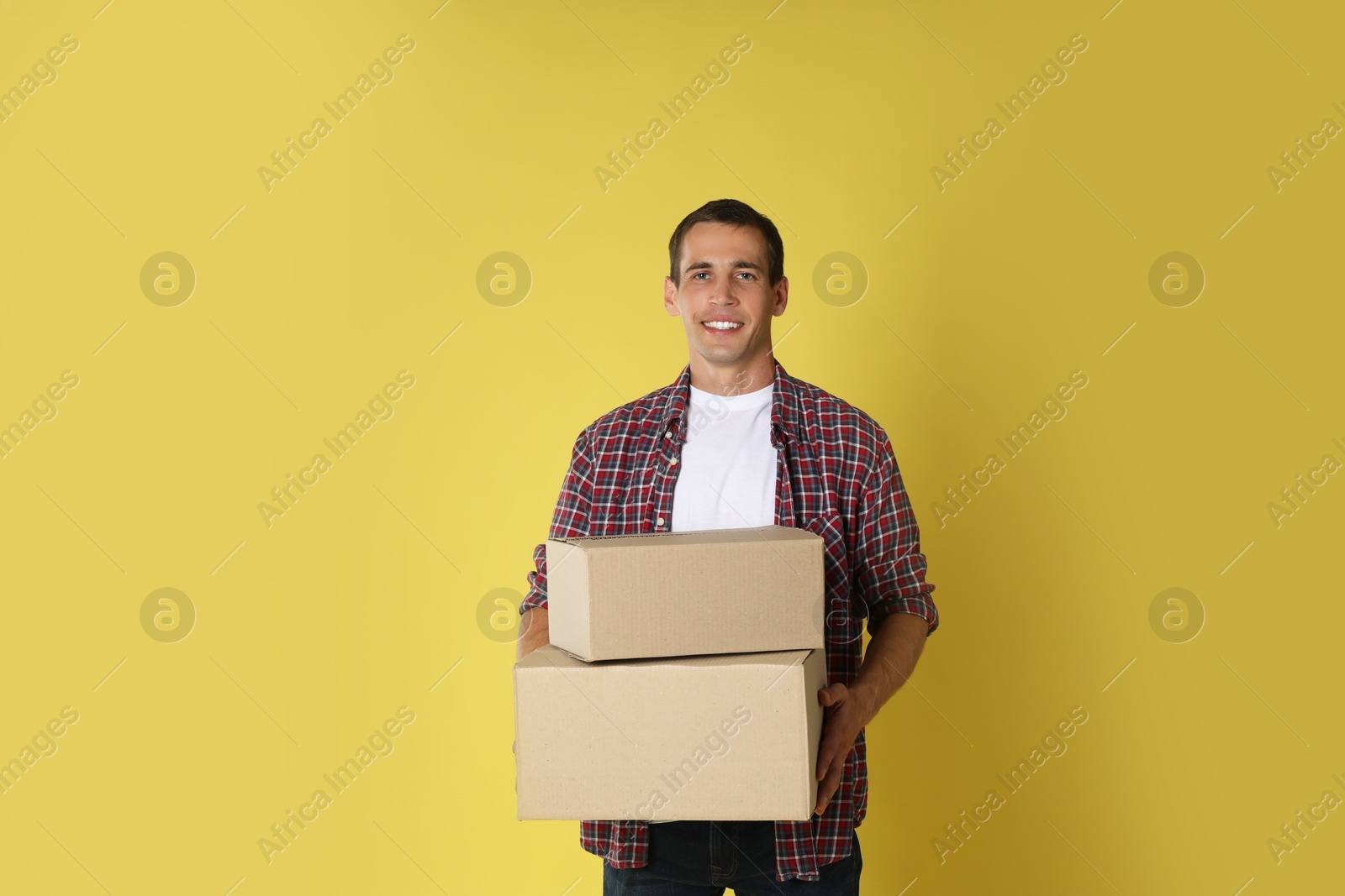 Photo of Moving into new house. Man with cardboard boxes on yellow background