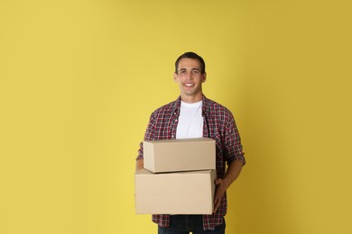 Photo of Moving into new house. Man with cardboard boxes on yellow background