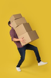 Photo of Moving into new house. Man with cardboard boxes on yellow background