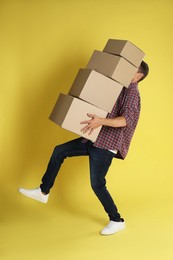 Moving into new house. Man with cardboard boxes on yellow background