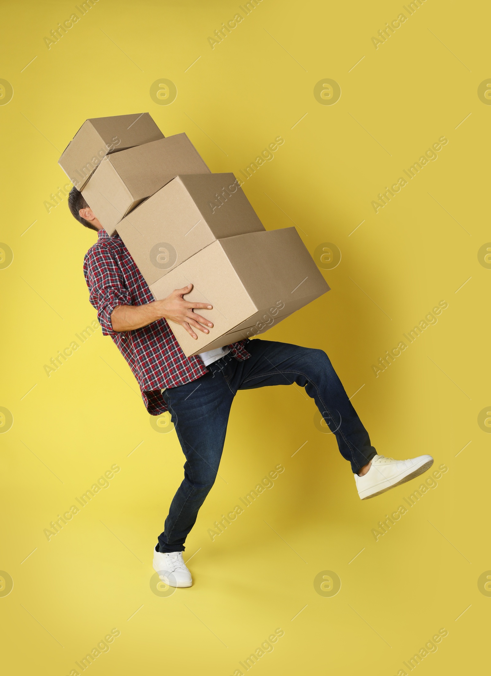 Photo of Moving into new house. Man with cardboard boxes on yellow background