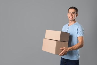 Photo of Moving into new house. Man with cardboard boxes on grey background, space for text