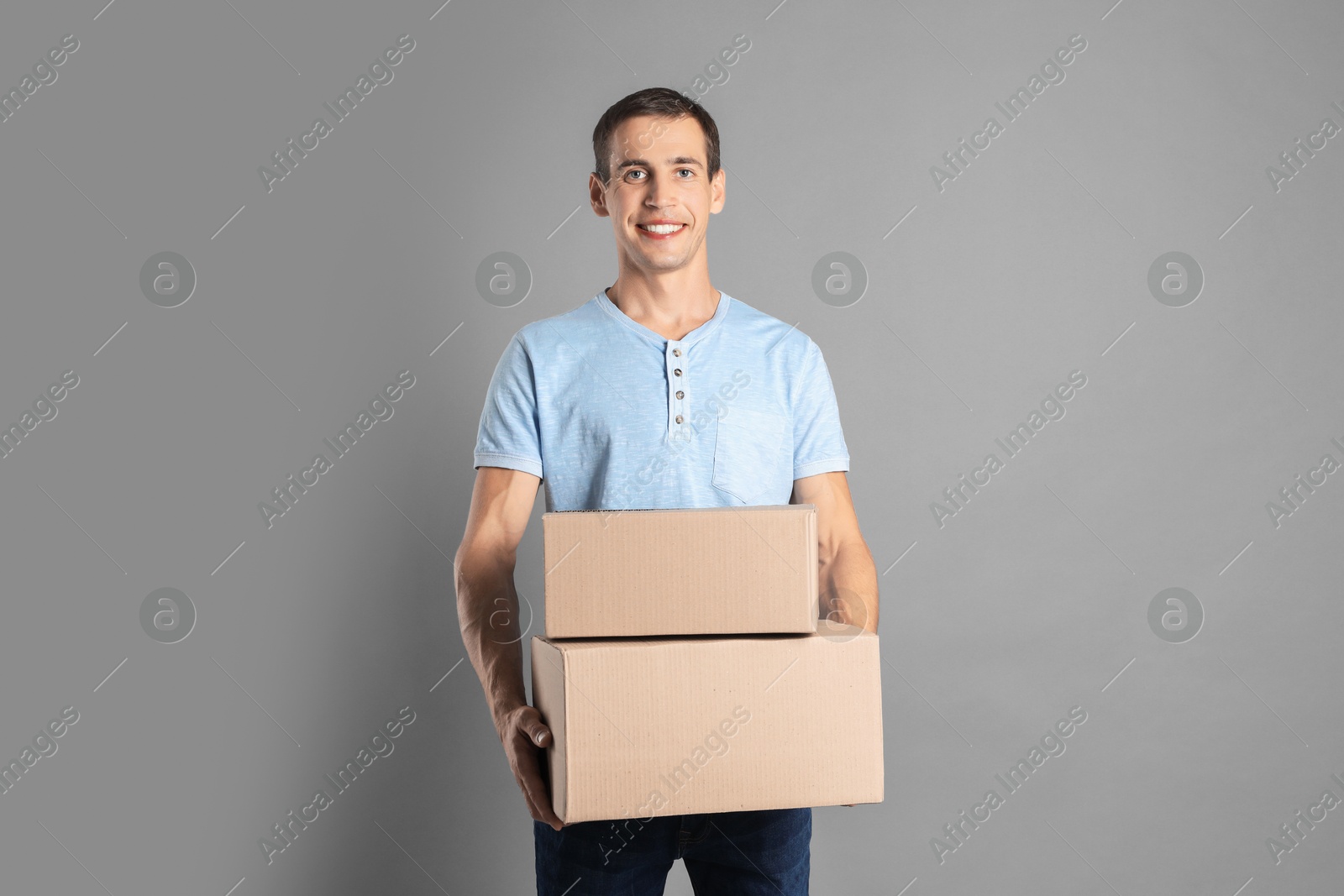 Photo of Moving into new house. Man with cardboard boxes on grey background, space for text