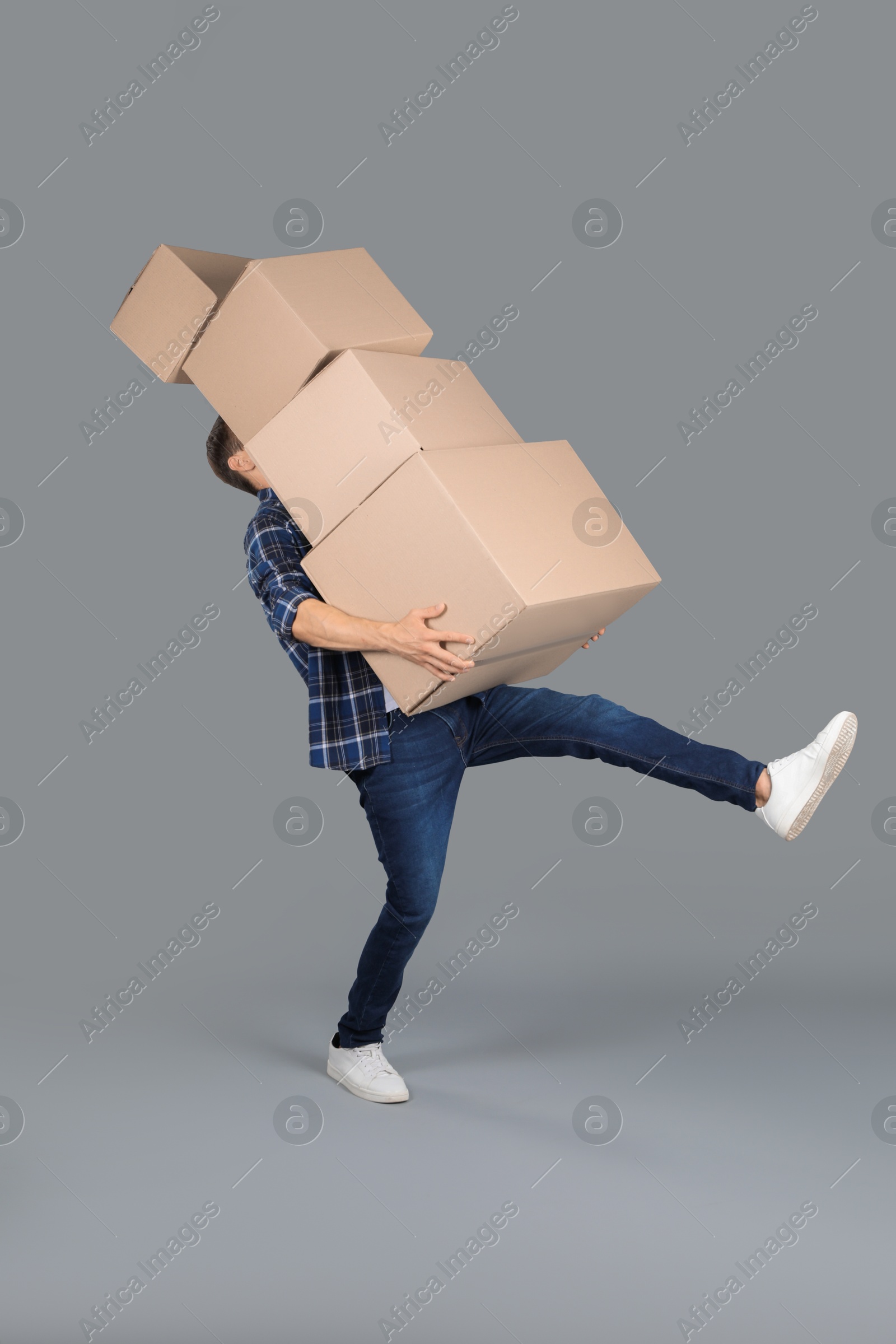 Photo of Moving into new house. Man with cardboard boxes on grey background