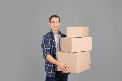 Photo of Moving into new house. Man with cardboard boxes on grey background