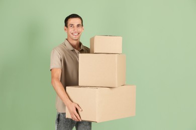 Photo of Moving into new house. Man with cardboard boxes on light green background