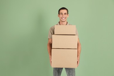 Photo of Moving into new house. Man with cardboard boxes on light green background