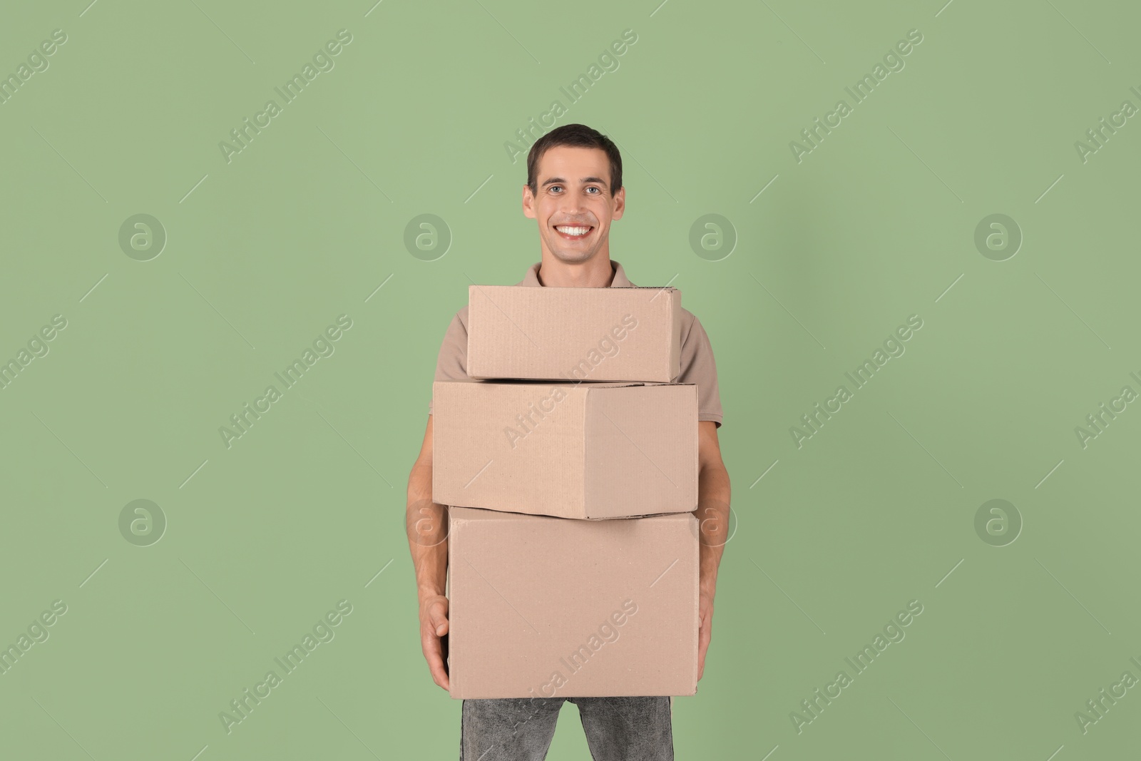 Photo of Moving into new house. Man with cardboard boxes on light green background, space for text