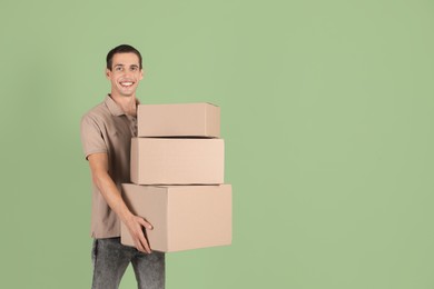 Photo of Moving into new house. Man with cardboard boxes on light green background, space for text