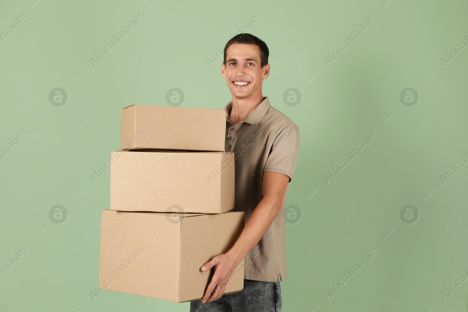 Photo of Moving into new house. Man with cardboard boxes on light green background, space for text