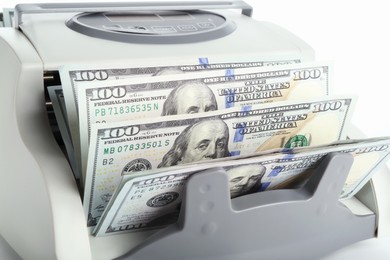 Photo of Money counter machine with dollar banknotes on white background, closeup