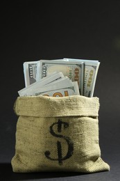 Photo of Dollar banknotes in burlap sack on dark background