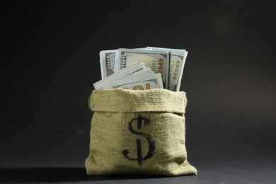 Photo of Dollar banknotes in burlap sack on dark background