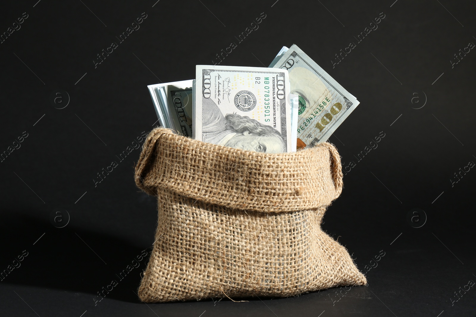 Photo of Dollar banknotes in burlap sack on dark background