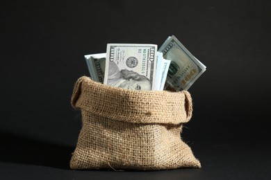 Photo of Dollar banknotes in burlap sack on dark background