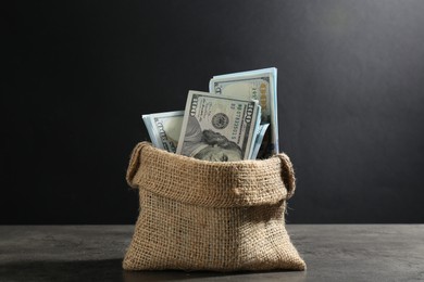 Photo of Dollar banknotes in burlap sack on grey table