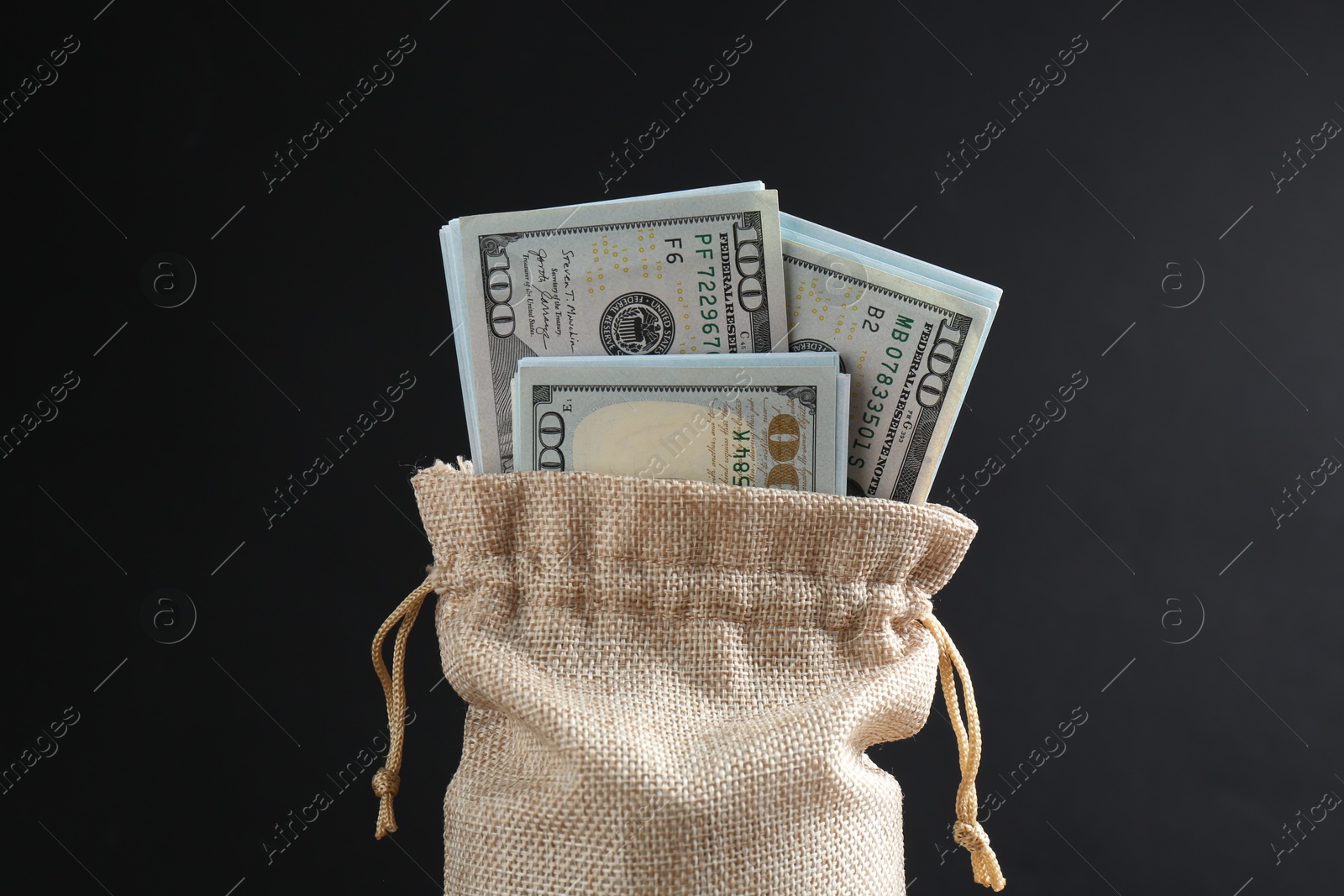 Photo of Dollar banknotes in burlap sack against dark background