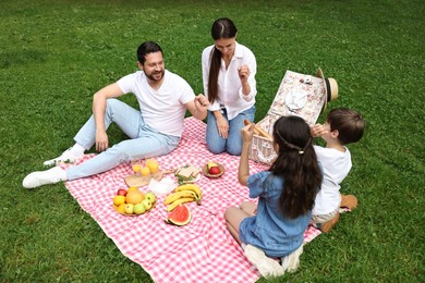 Photo of Happy family playing rock, paper and scissors during picnic in park