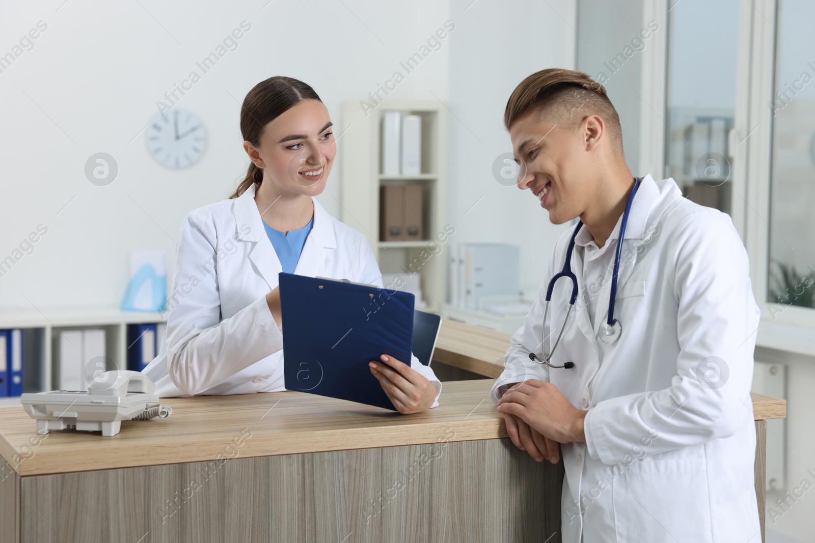 Photo of Professional receptionist and doctor at wooden desk in hospital