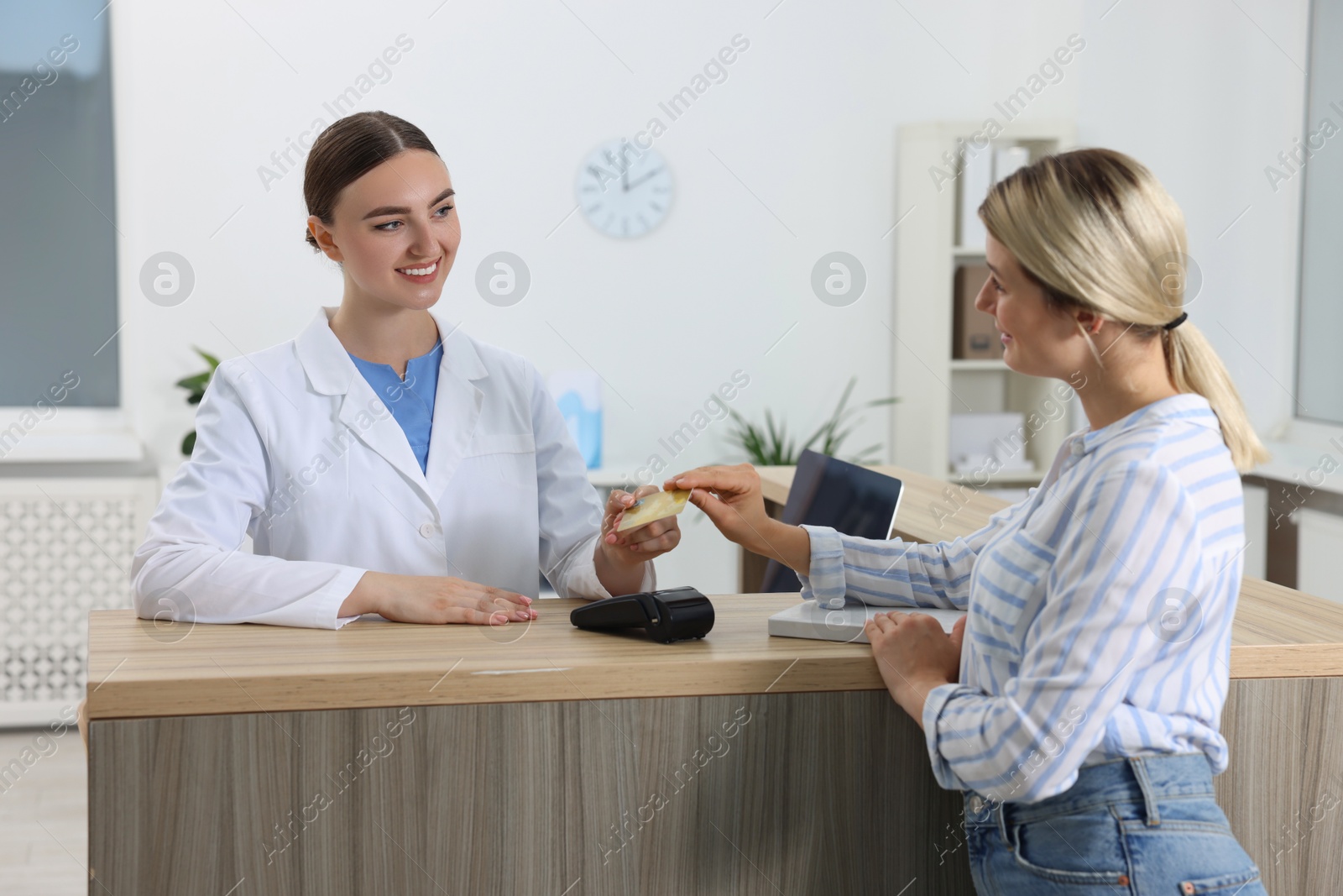 Photo of Receptionist taking payment from client via terminal at hospital