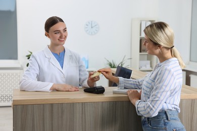 Receptionist taking payment from client via terminal at hospital