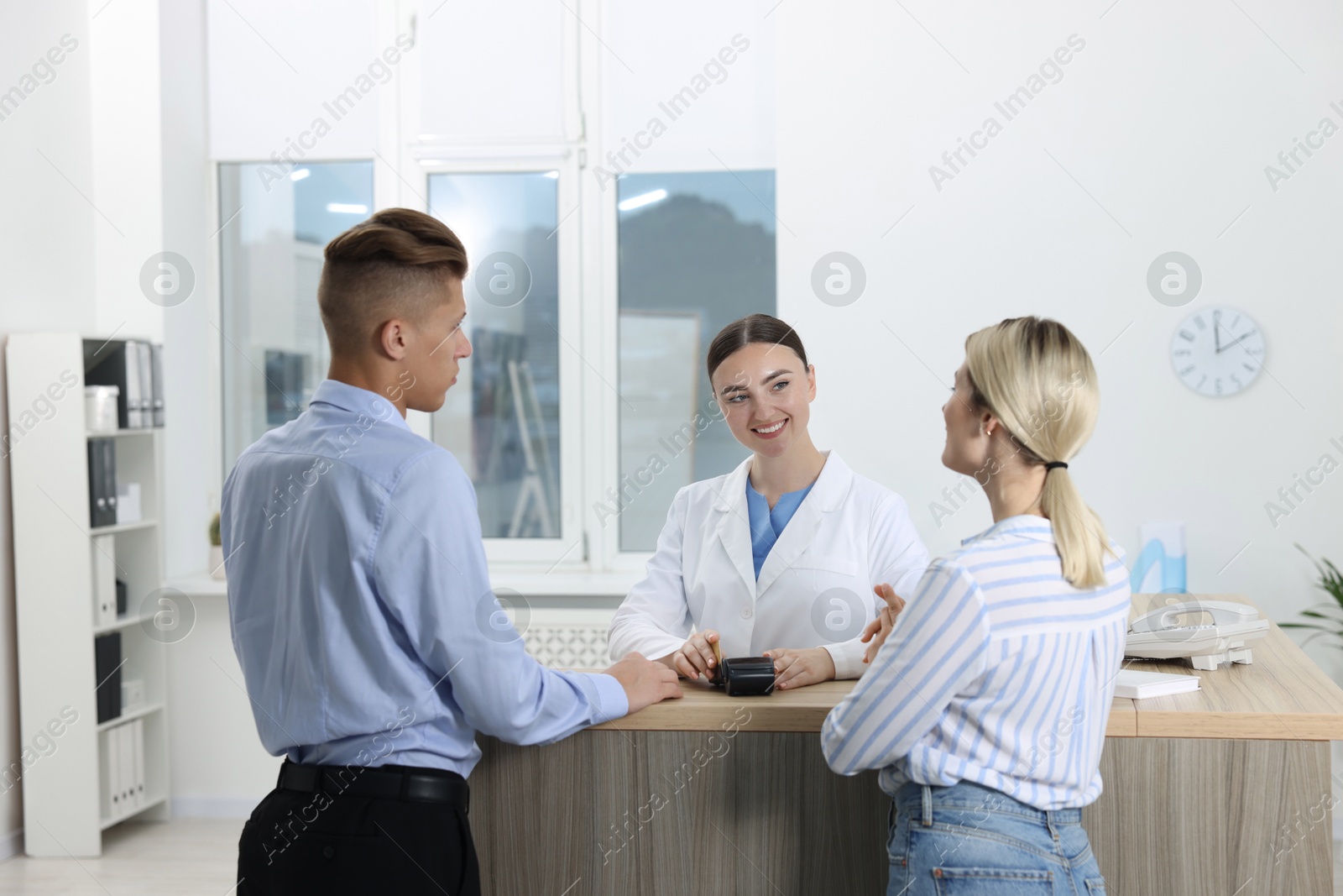 Photo of Receptionist taking payment from client via terminal at hospital