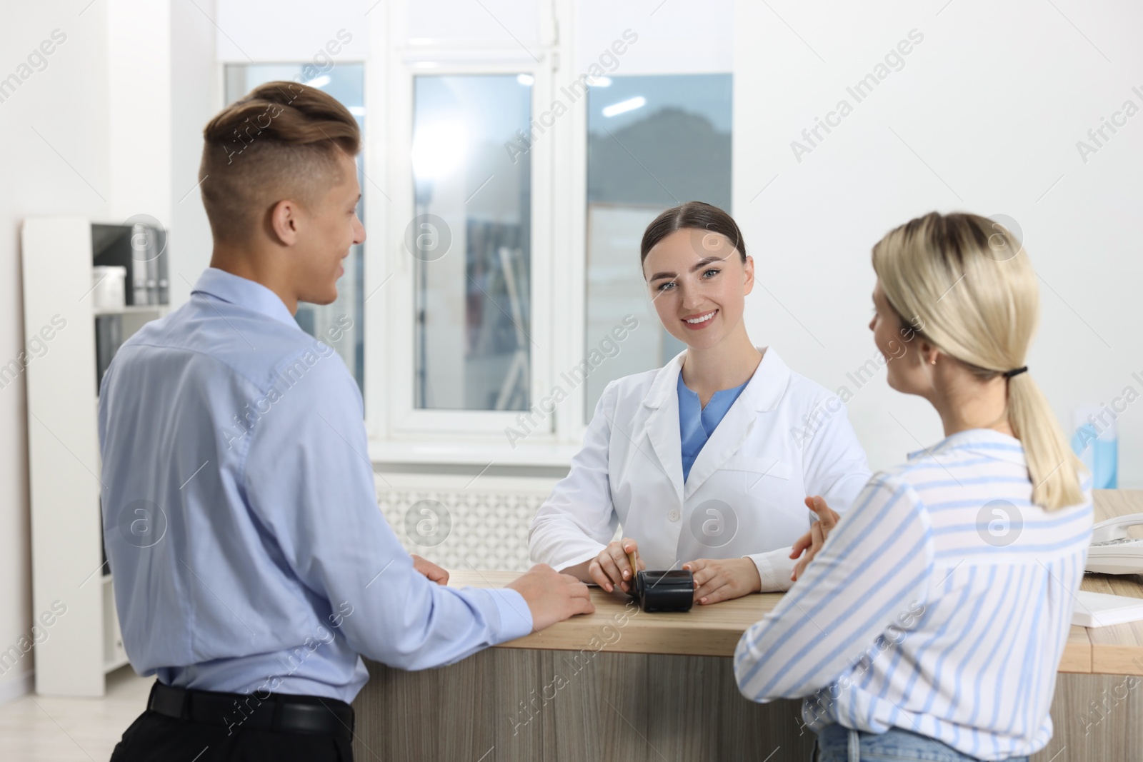 Photo of Receptionist taking payment from client via terminal at hospital