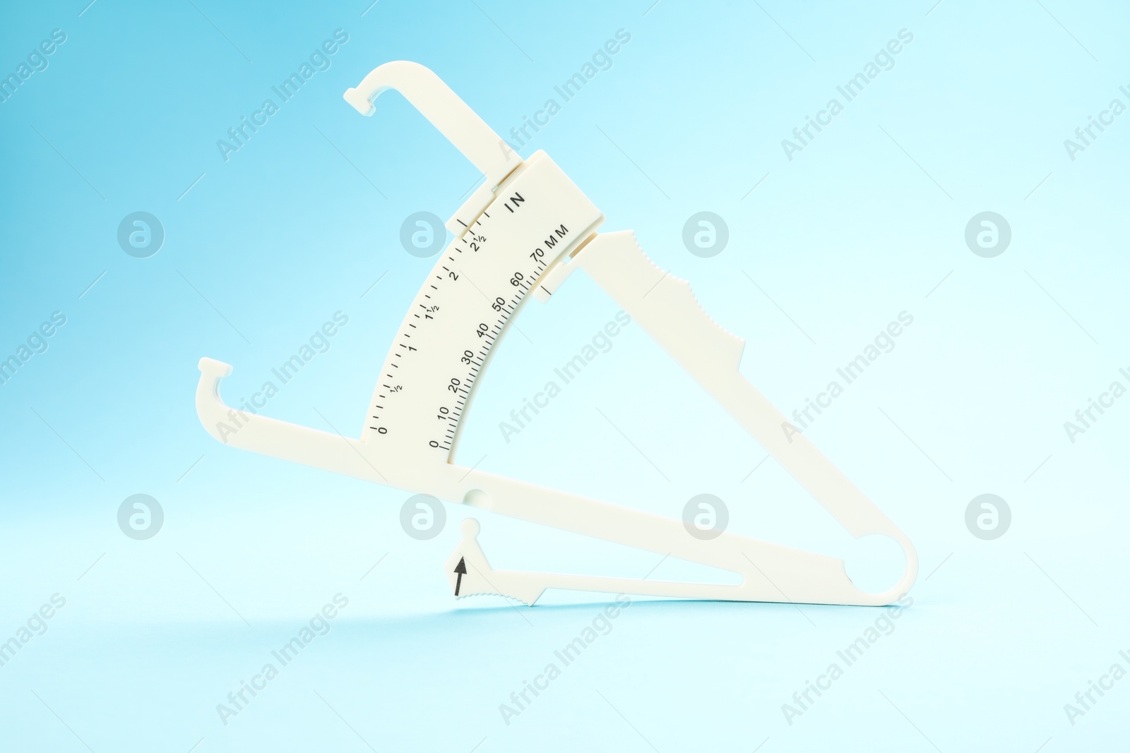 Photo of Plastic body fat caliper on light blue background