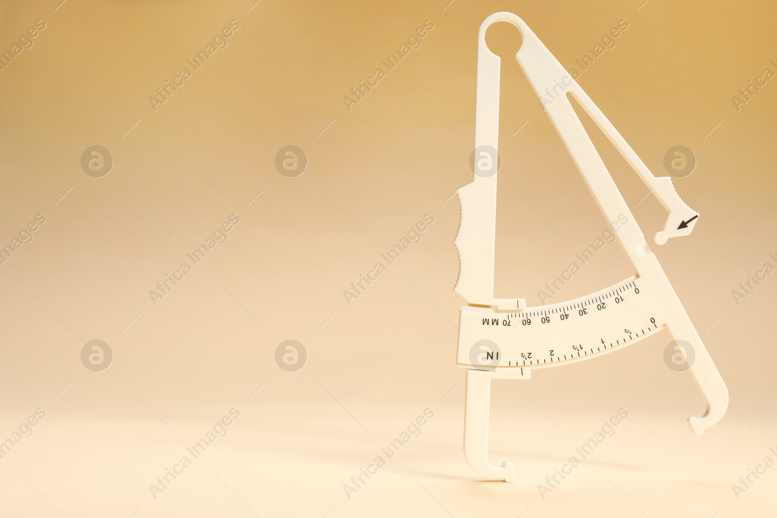 Photo of Plastic body fat caliper on beige background. Space for text