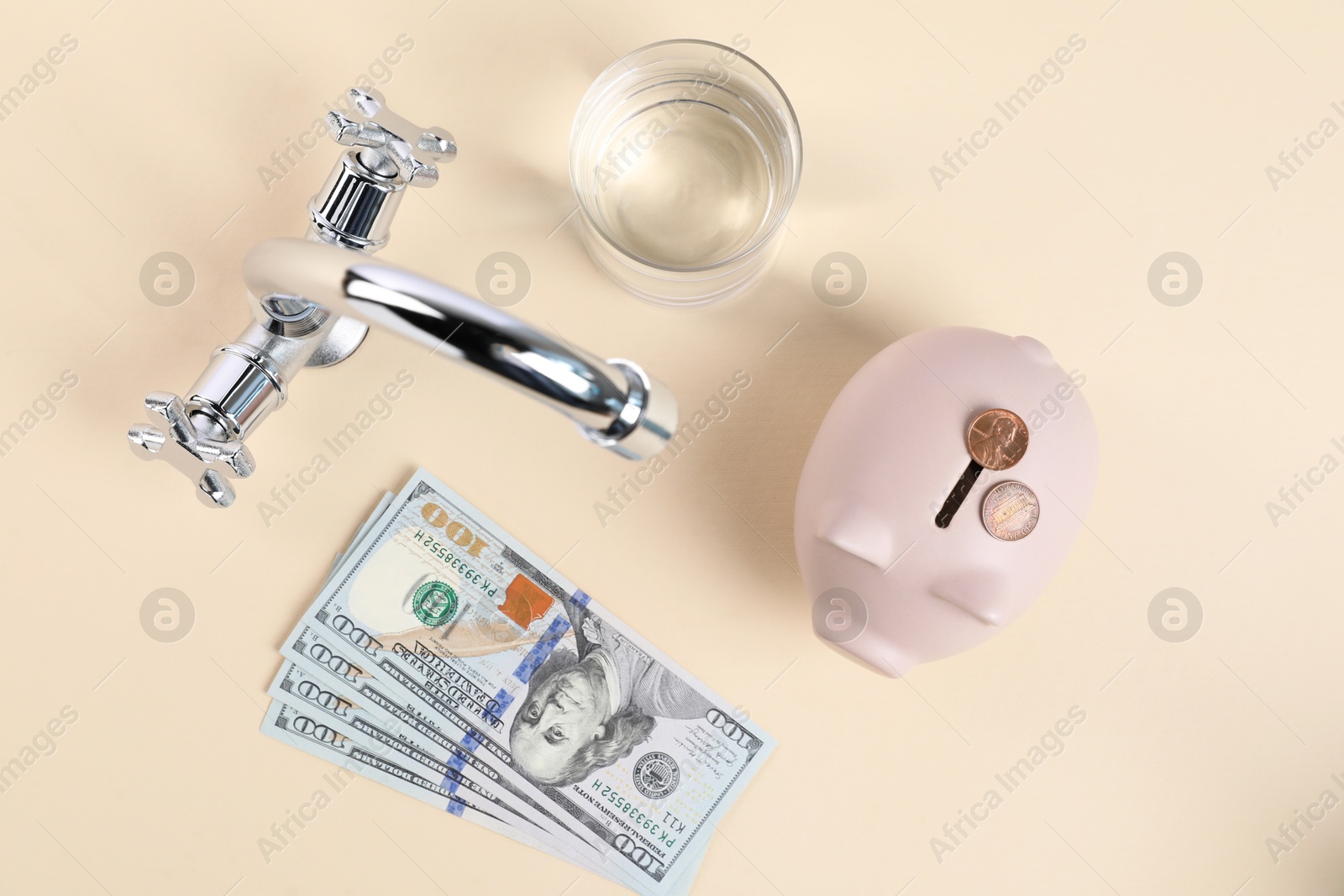 Water saving concept. Piggy bank, tap, glass of drink, dollar banknotes and coins on pale yellow background, flat lay Photo of Water saving concept. Piggy bank, tap, glass of drink, dollar banknotes and coins on pale yellow background, flat lay