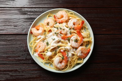 Photo of Delicious pasta with shrimps and creamy sauce on wooden table, top view