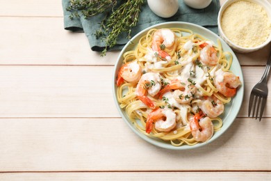 Delicious pasta with shrimps and creamy sauce served on light wooden table, flat lay. Space for text