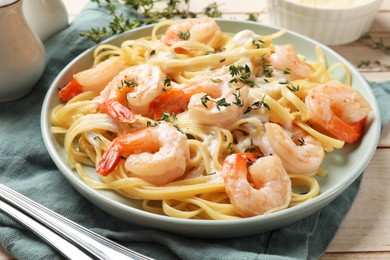 Photo of Delicious pasta with shrimps and creamy sauce served on wooden table, closeup