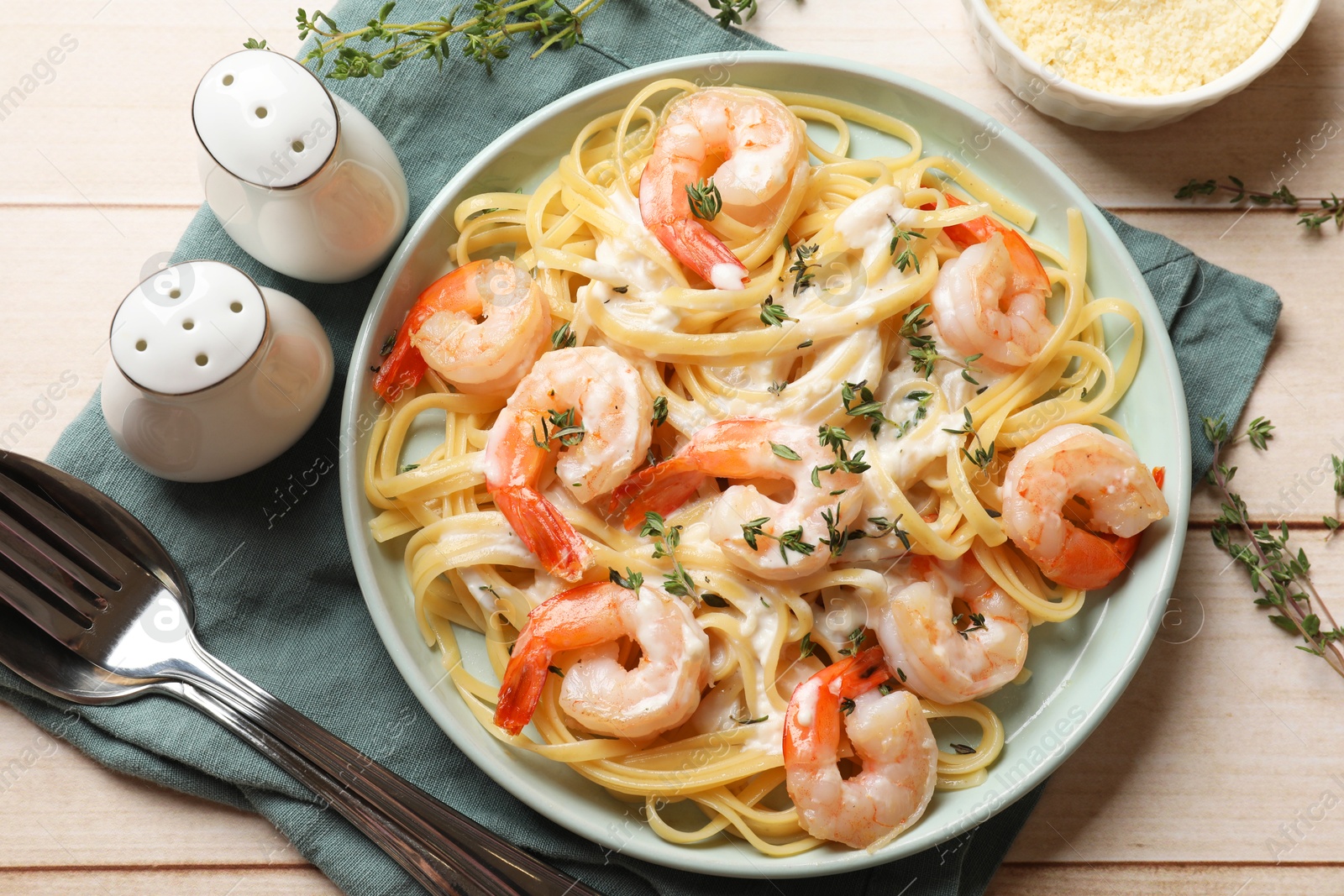 Photo of Delicious pasta with shrimps and creamy sauce served on light wooden table, flat lay