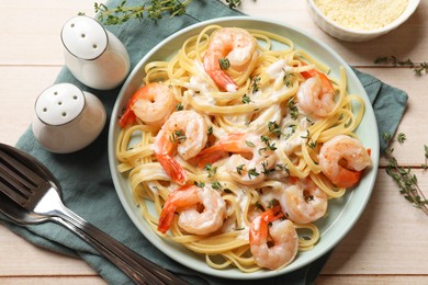 Photo of Delicious pasta with shrimps and creamy sauce served on light wooden table, flat lay