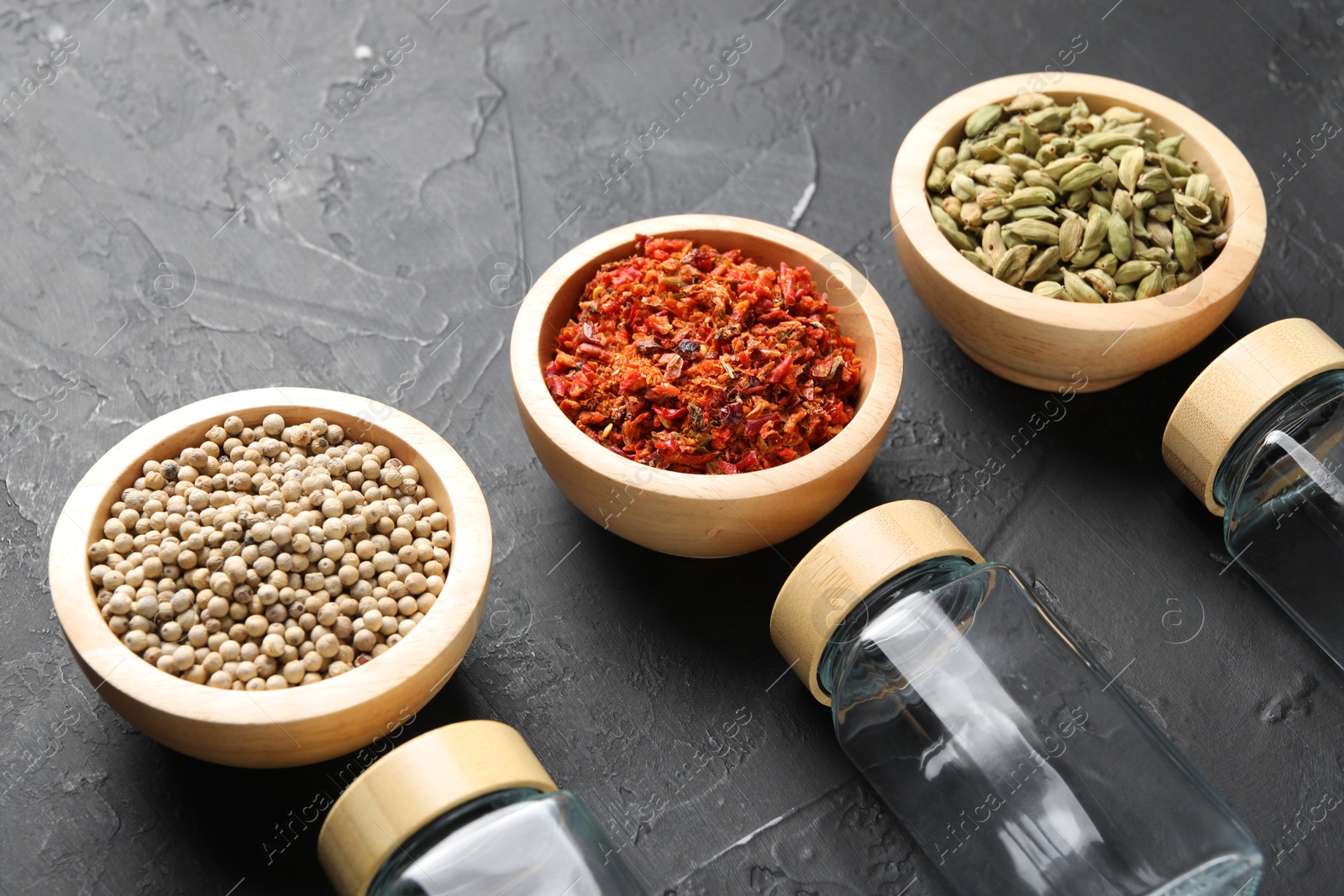 Photo of Different spices and glass jars on black table