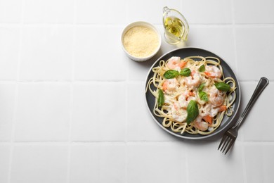 Photo of Tasty pasta with shrimps served on white tiled table, flat lay. Space for text