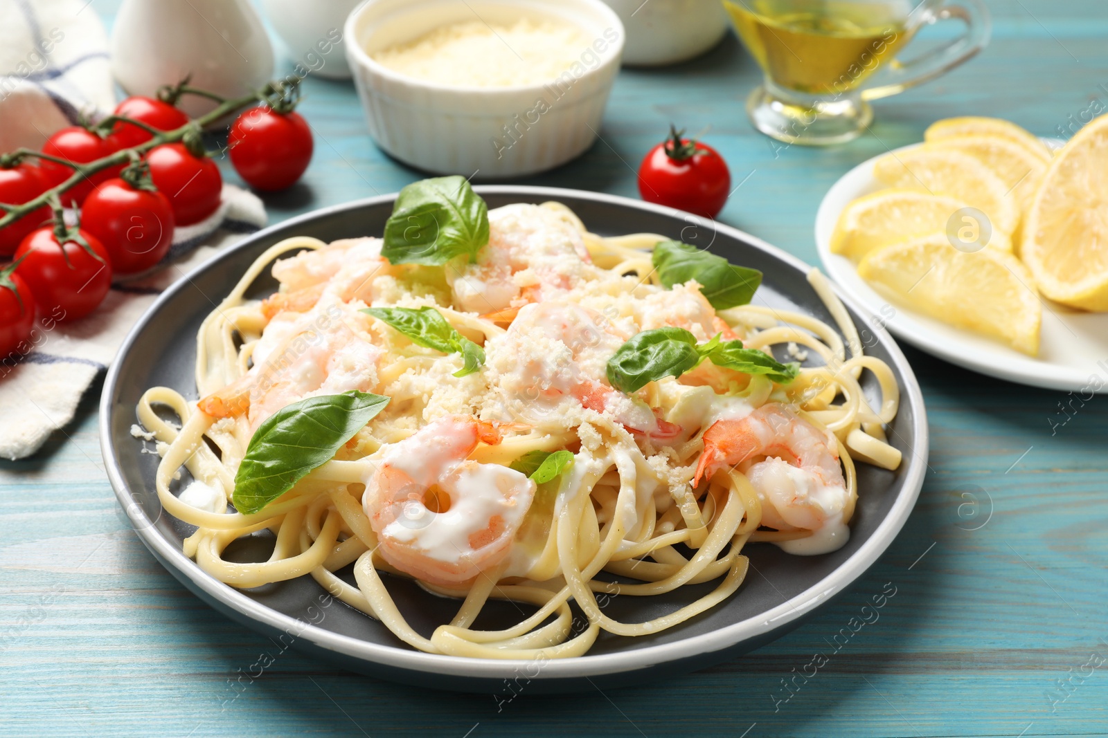 Photo of Tasty pasta with shrimps on light blue wooden table, closeup