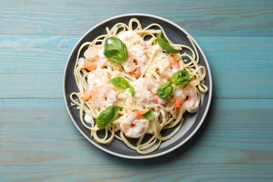 Photo of Tasty pasta with shrimps on light blue wooden table, top view